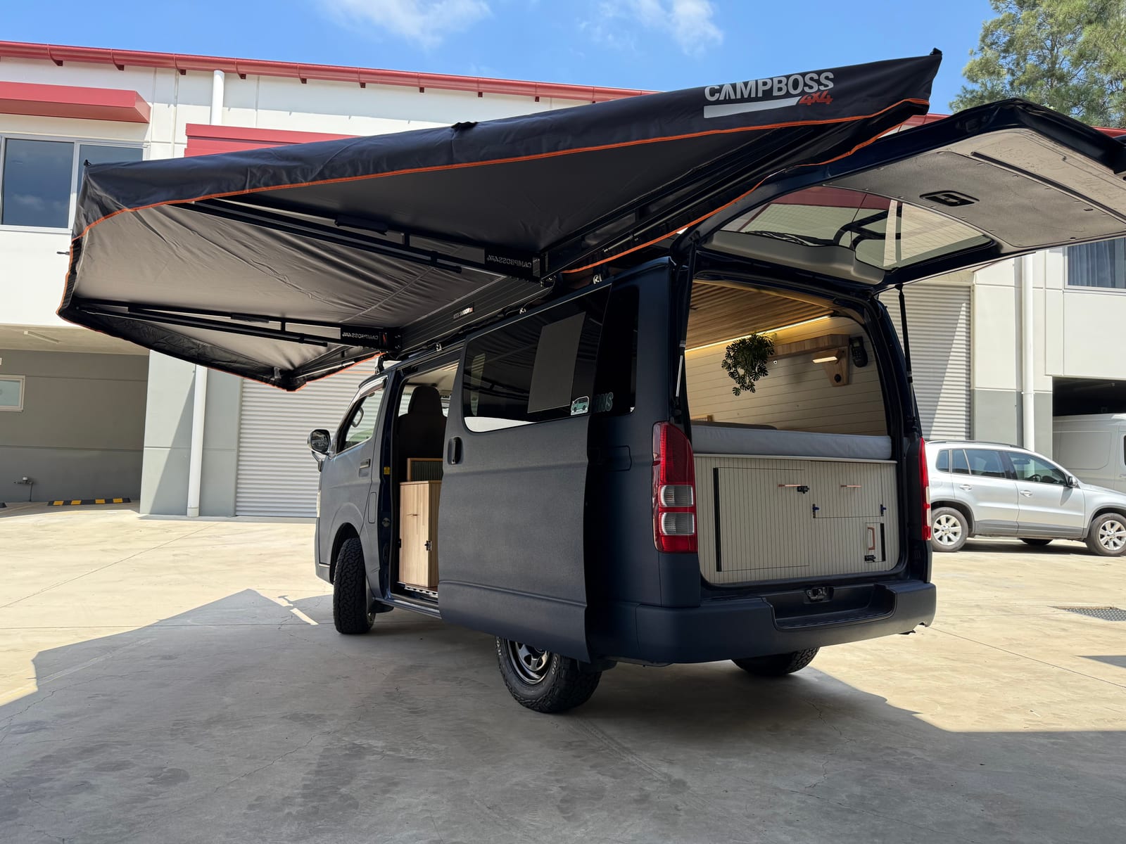 Slate Blue Hiace &mdash; Side on, awning fully extended
