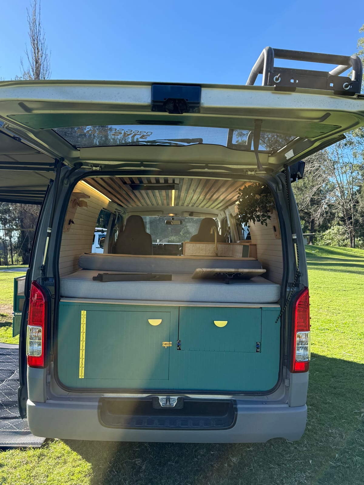 Teal Galley Hiace — Rear doors open onto the bed